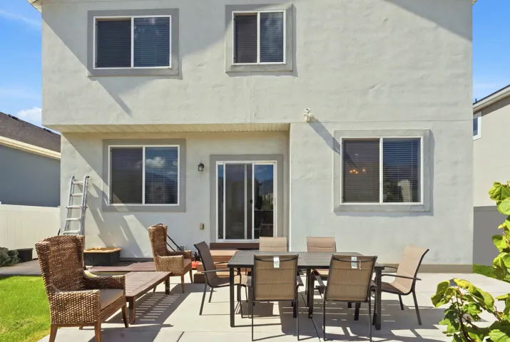 Rear exterior featuring stucco finish, sliding glass door, and a concrete patio
