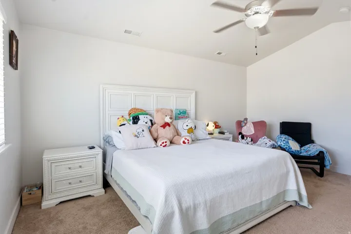 Vaulted ceiling with a ceiling fan, carpeted flooring, and a white paneled headboard