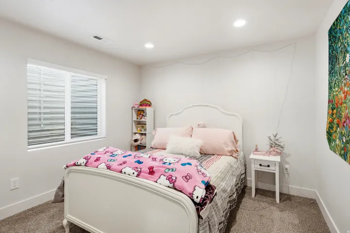 Recessed ceiling lighting illuminates a window with horizontal blinds and a gray carpeted floor