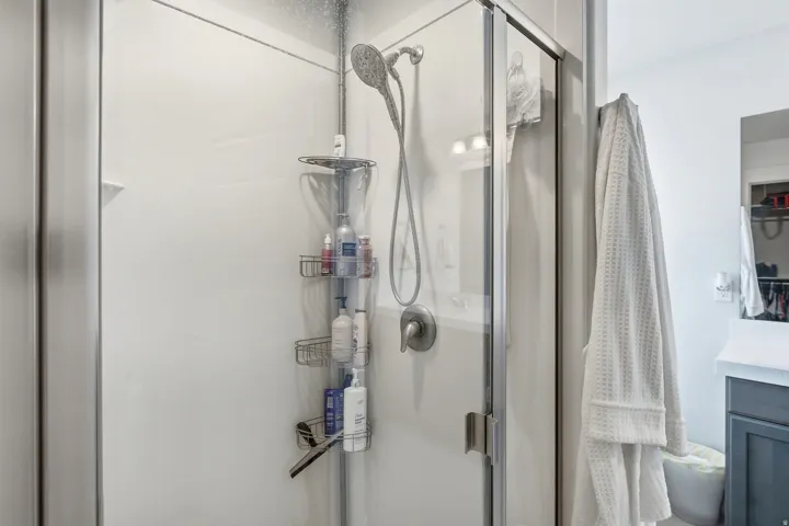 Shower enclosure with glass door, wall-mounted showerhead, and brushed nickel fixtures