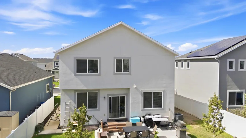 Rear exterior featuring a ground-level patio, wood deck, and upper-level windows