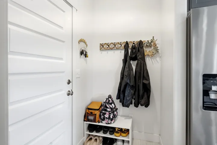 Recessed panel door with polished chrome hardware, durable wall-mounted coat rack, and stainless steel refrigerator