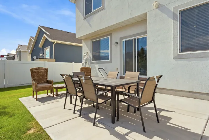 Stucco exterior with sliding patio door, concrete patio, and fenced yard
