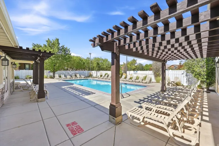 Swimming pool with concrete surround, multiple pergolas, and white fencing