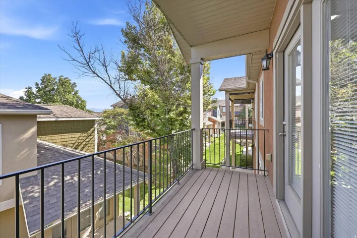 Balcony with composite decking, black metal railing, and an exterior wall light fixture