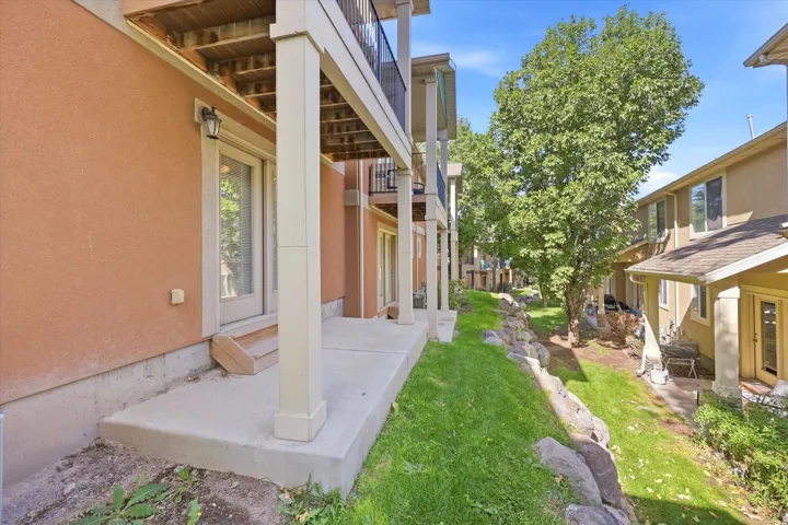 Covered patio with concrete flooring, stucco exterior, and a built-in exterior light fixture