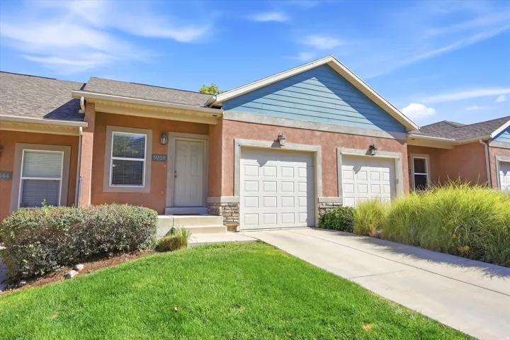 Exterior featuring stucco siding, stone accents, two paneled garage doors, and a concrete driveway