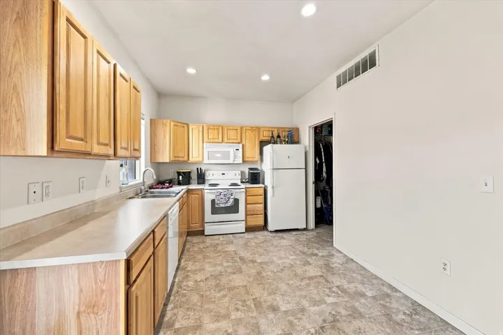 Kitchen featuring wood-finish cabinetry, solid surface countertops, a stainless steel sink, and recessed lighting
