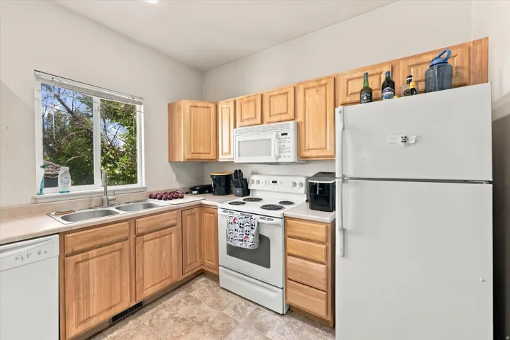 Full kitchen featuring wood cabinetry, laminate countertops, a double basin sink, and a window