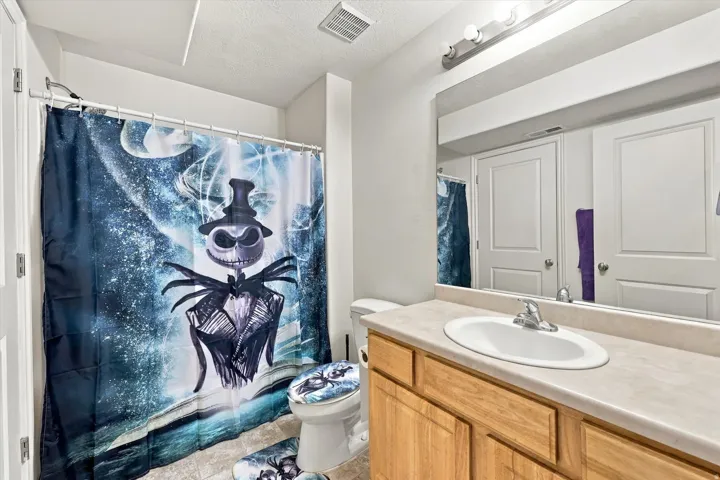 Vanity with an integrated sink, wood-finish cabinetry, and an expansive wall-mounted mirror
