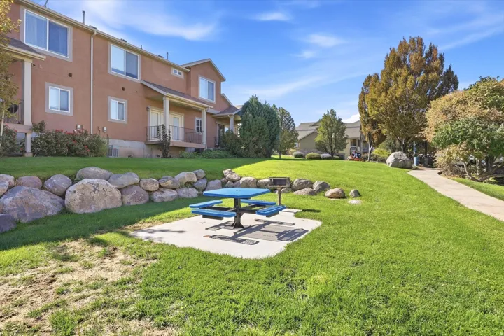 Expansive green space featuring a concrete patio, built-in grill, and stone retaining wall