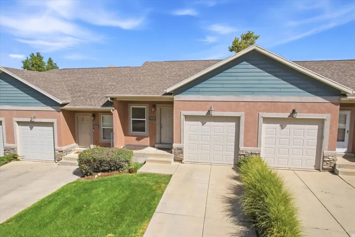 Multi-unit exterior with individual attached garages, stucco siding, and stone accents