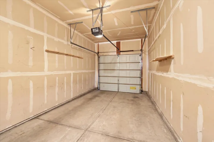 Concrete flooring, overhead garage door, built-in shelving, and garage door opener system