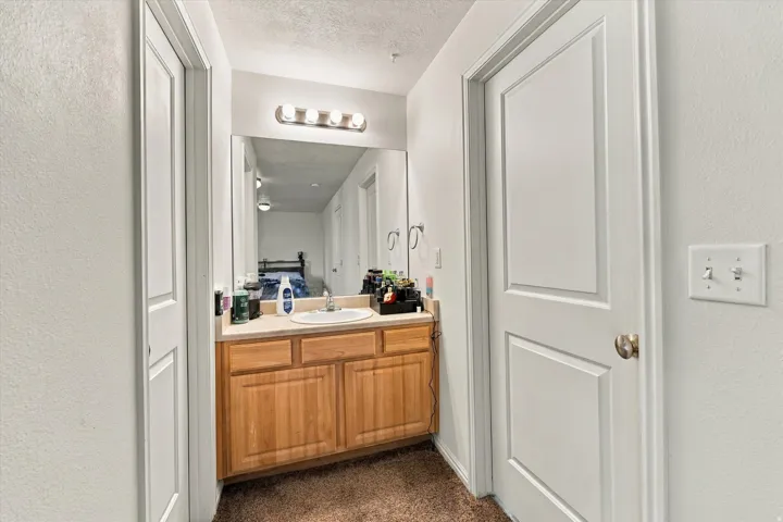 Vanity area featuring a wood-finish cabinet, rectangular sink, and wall-mounted light fixture