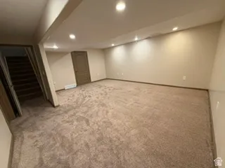 Recessed lighting throughout, carpeted flooring, and a paneled interior door