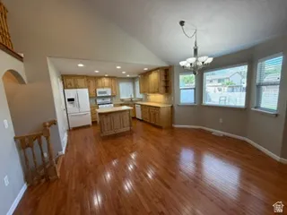 Wood-finish flooring, vaulted ceiling, wood cabinetry, kitchen island, and recessed lighting
