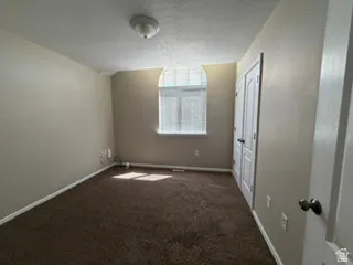 Arched window with blinds, brown carpet, neutral wall paint, white trim, and white paneled doors