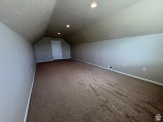 Expansive carpeted area with sloped ceilings and recessed lighting