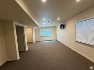 Recessed ceiling lighting, textured walls, carpet flooring, and two windows with blinds