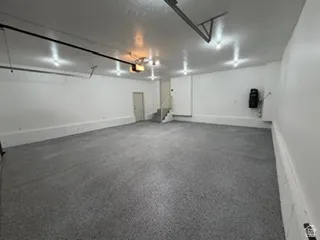 Spacious garage with textured gray flooring, white painted walls, and overhead lighting