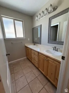 Dual vanity with light wood-finish cabinetry, integrated sinks, individual framed mirrors, and a window for natural illumination