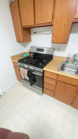 Stainless steel range, wood-finish cabinetry, light-colored countertops, and patterned floor tiling