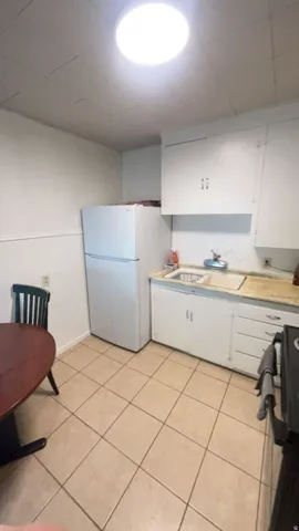 Kitchen with tile flooring, white cabinetry, and a drop-in sink