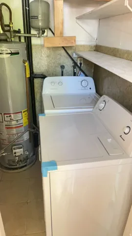 Laundry area featuring a water heater, tiled flooring, and wall-mounted shelving