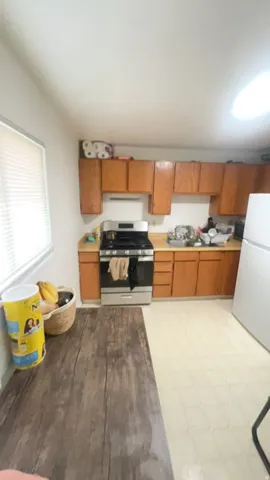 Kitchen featuring wood-finish cabinetry, stainless steel range, and window with blinds
