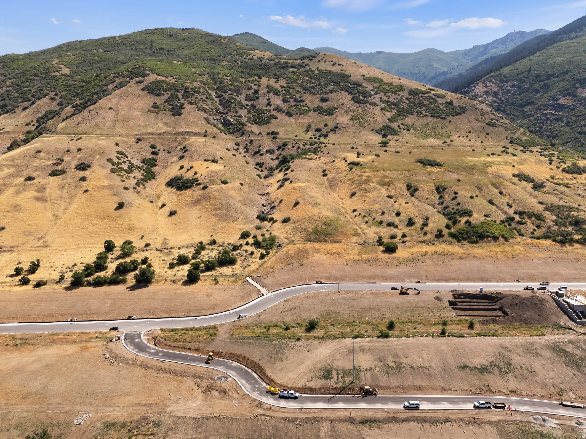 Mountainous terrain, winding paved roads, excavated building sites, natural landscape