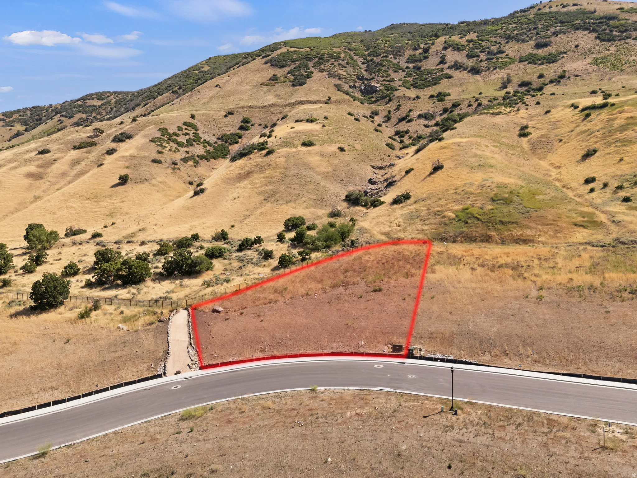 Graded property with a paved roadway and surrounding hills