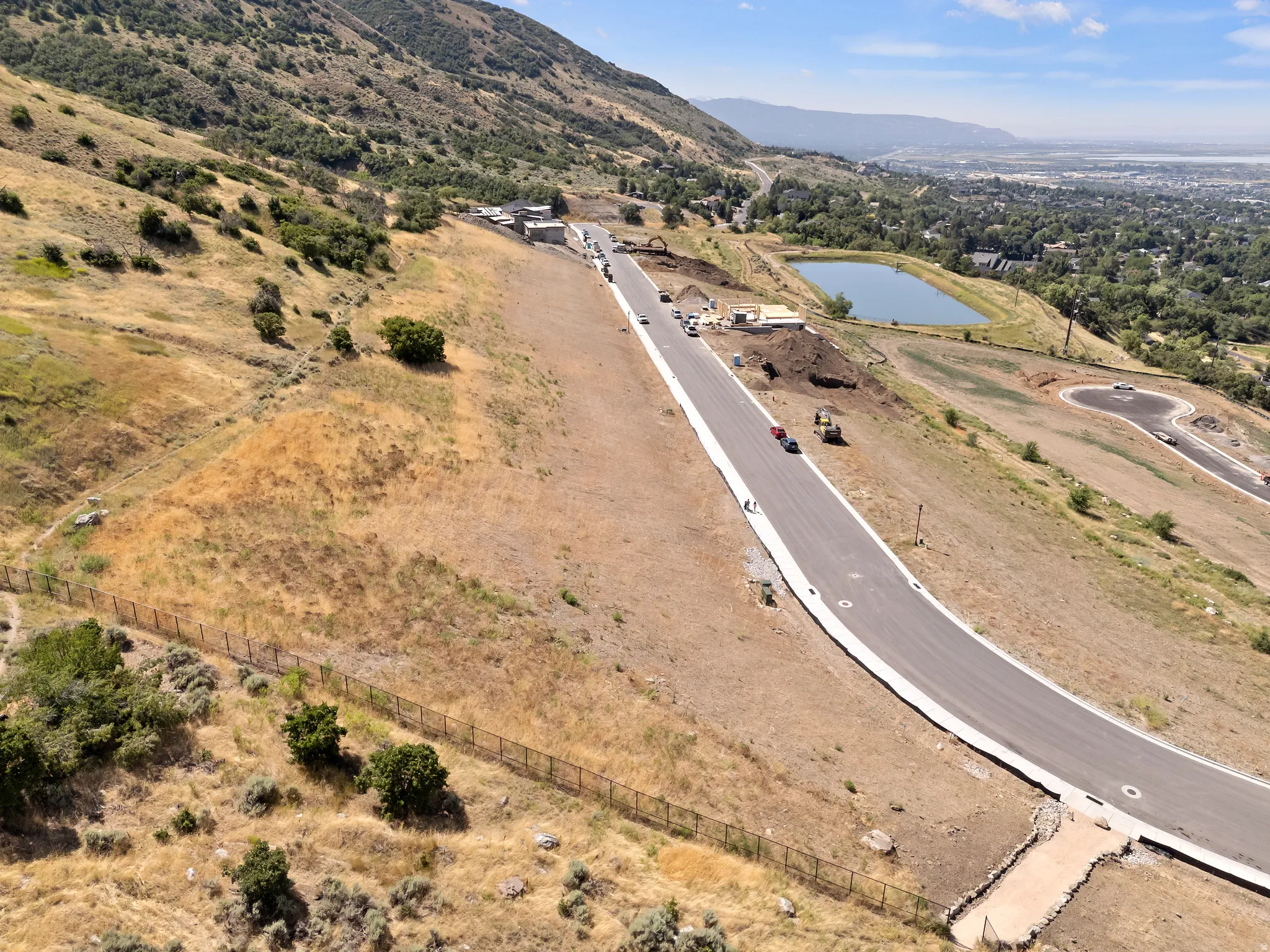 Paved road with curbs, hillside terrain, and distant water feature