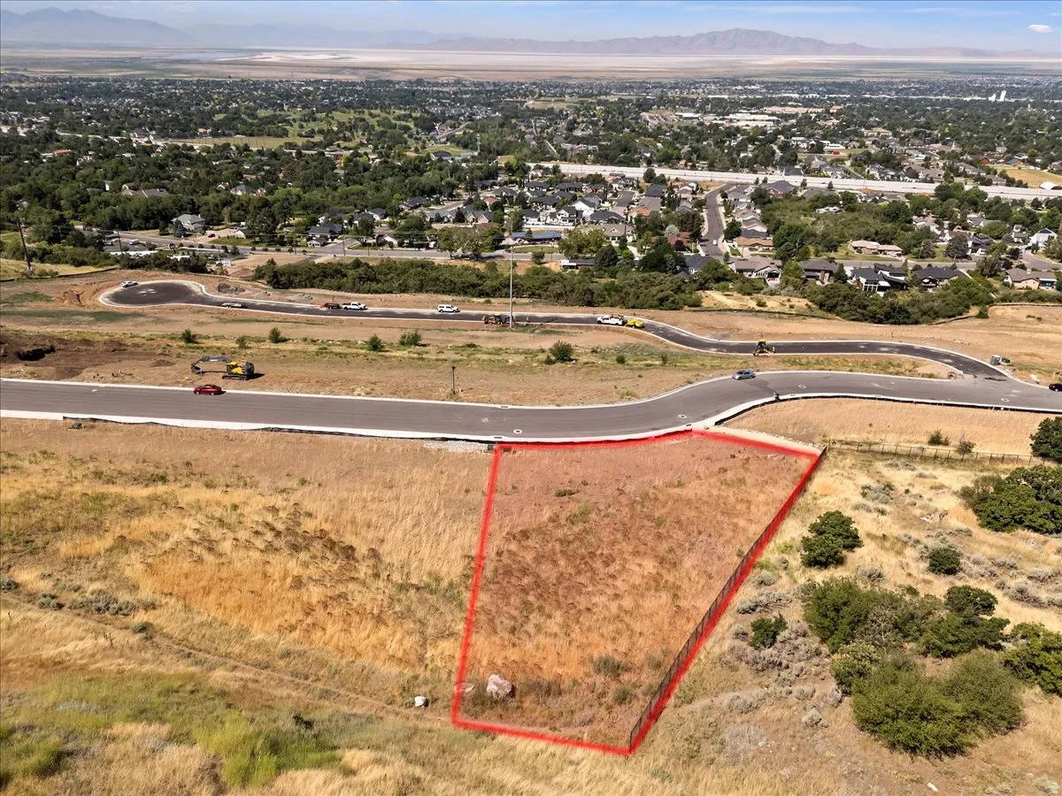 Expansive undeveloped lot with street frontage, surrounded by established residential areas and distant mountains