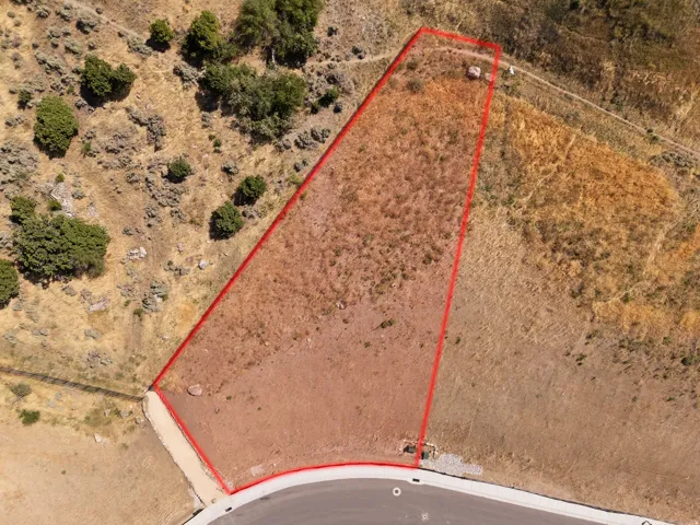 Curved paved road frontage, defined property boundaries, natural terrain, and surrounding undeveloped landscape