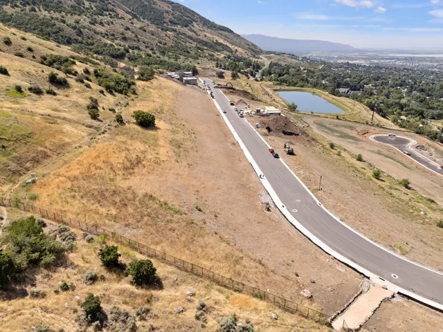 Paved road with curbs, hillside terrain, and distant water feature