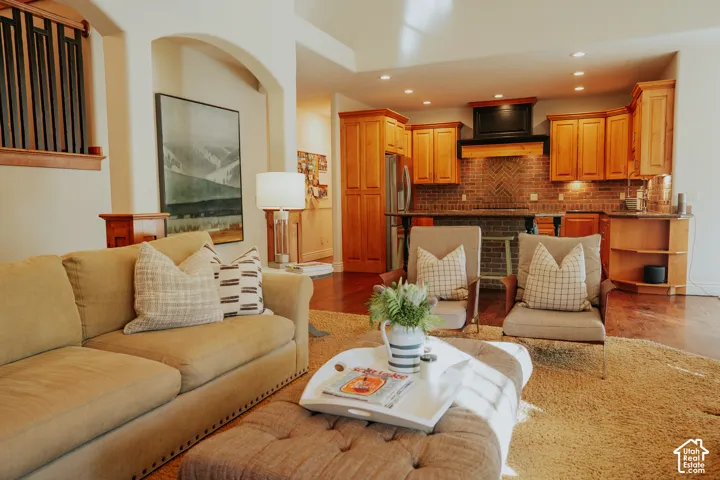 Open-concept living area featuring hardwood flooring, arched doorways, and recessed lighting