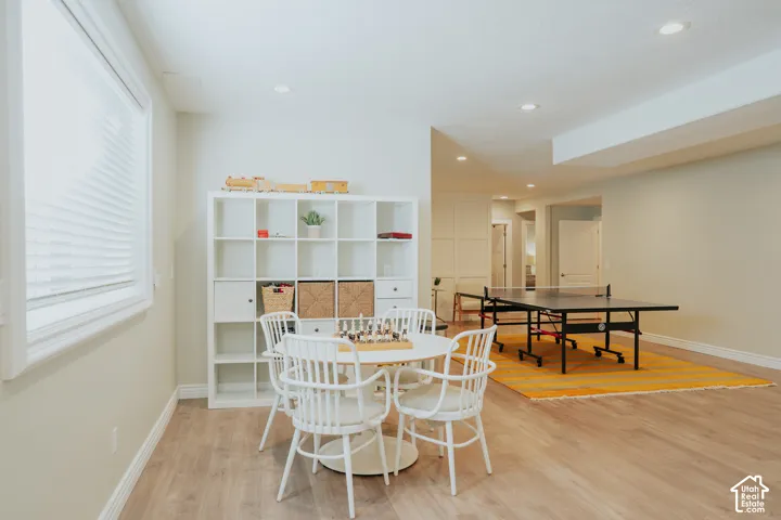 Recessed lighting illuminating wood-finish flooring, a window with blinds, and white built-in shelving