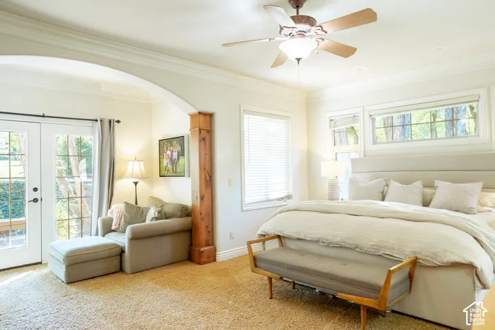 Archway entry with a wood-finish column, double French doors, large windows, ceiling fan, and crown molding