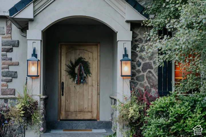 Arched entry with a wood-plank door, stone and stucco exterior, and two exterior lanterns