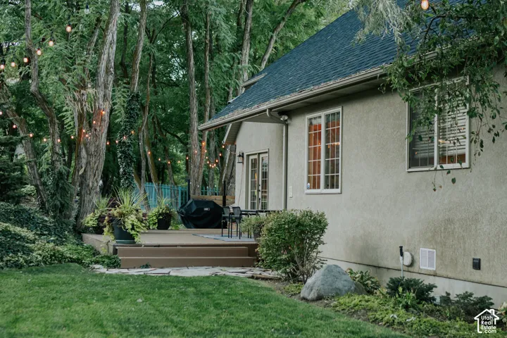 Exterior stucco finish, composite decking, multiple windows, and a shingle roof