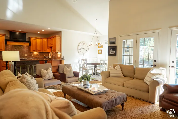 Vaulted ceiling, recessed lighting, wood cabinetry, brick-patterned backsplash, and double French doors with transom windows