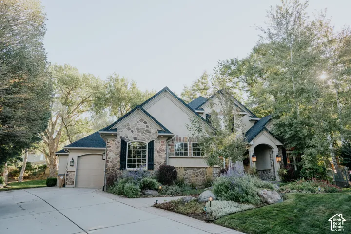 Stone and stucco exterior with dark shingle roofing