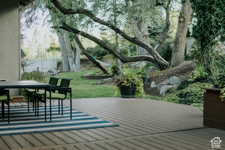 Spacious outdoor deck with grooved decking, providing access to a landscaped yard with mature trees