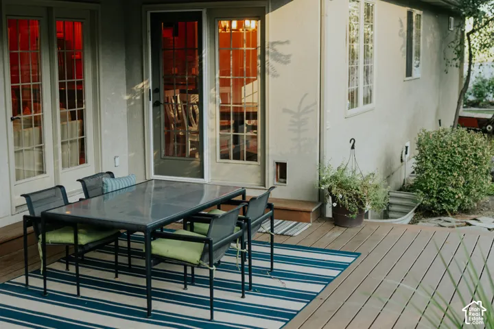 Expansive wood-finish decking, multiple glass-paned doors, and stucco exterior