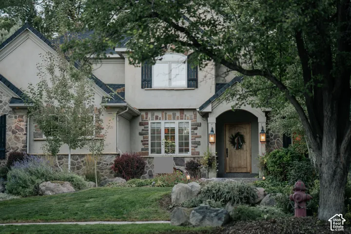 Stucco and stone exterior with architectural shingles, featuring a natural wood-finish front door with an arched entry