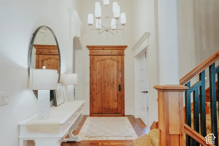 High ceilings with crown molding, wood-finish flooring, natural wood doors, and a staircase with wood newel posts and handrails
