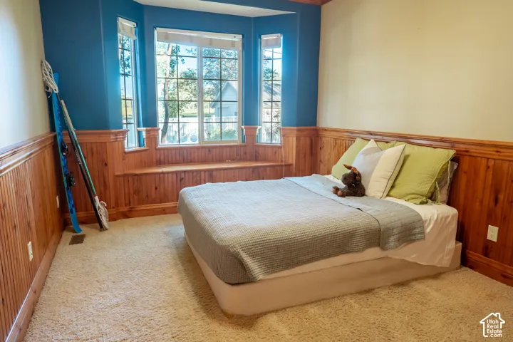 Bay window with an integrated window seat, wood-finish wainscoting, and carpet flooring
