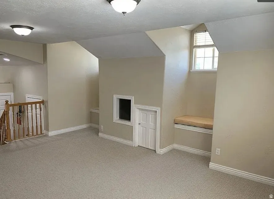 Carpeted room featuring a built-in window bench, interior window, and small interior door