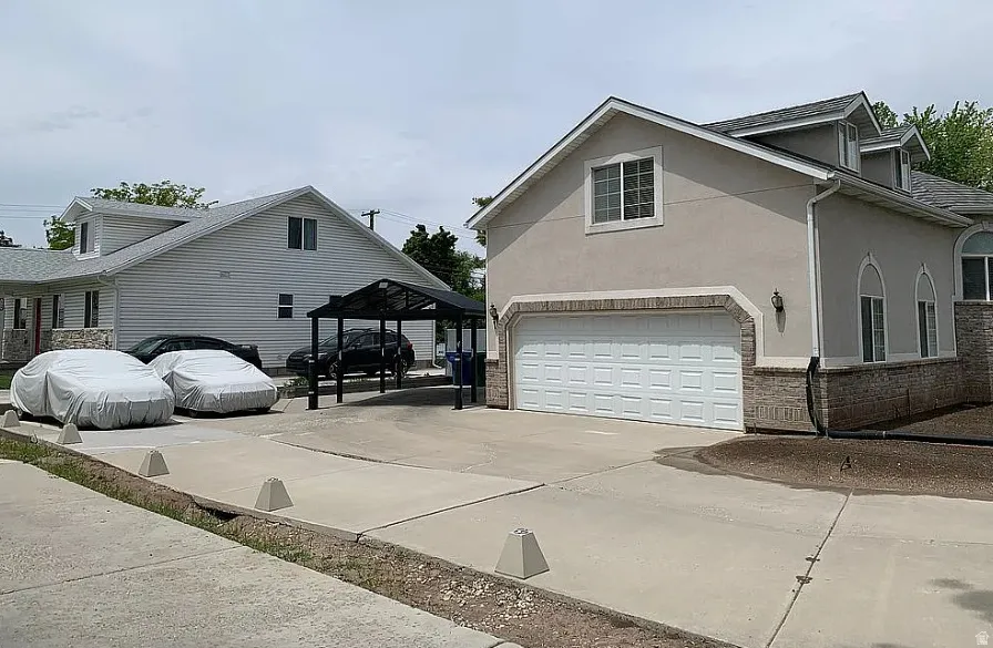 Stucco and stone exterior with arched window accents, attached garage, and paved driveway