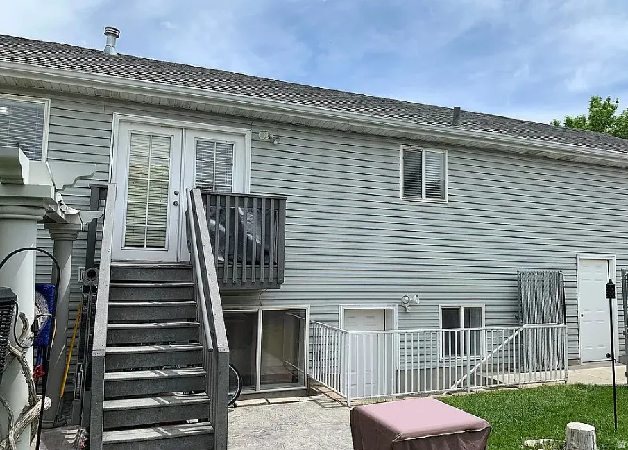 Exterior featuring light blue siding, a shingled roof, and a second-story balcony with composite decking